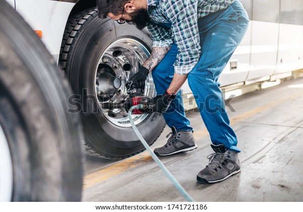Mechanic worker changing tires on bus. Vehicle\
repair service.