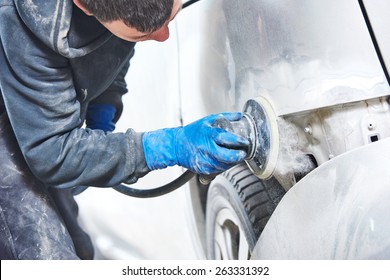 mechanic worker repairman sanding polishing car body and preparing automobile for painting during repair and renew at service station shop 
