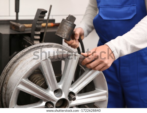 Mechanic working with car disk lathe machine at\
tire service, closeup