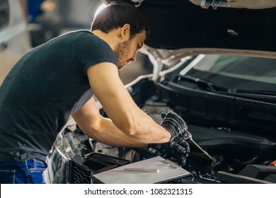 Mechanic Working In Car Hood In Garage