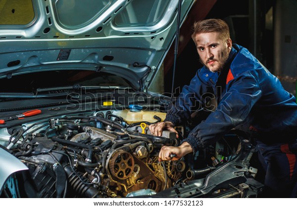Mechanic working in car motor. Auto repair,\
Service center. Mechanic with wrench working and repair car engine\
in car service centre.