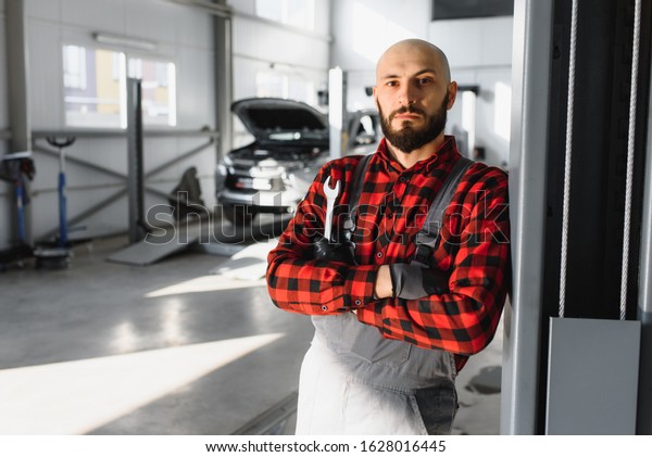 Mechanic working and holding wrench of\
service order for maintaining car at the repair\
shop