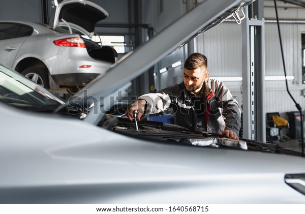 Mechanic working and holding wrench of
service order for maintaining car at the repair
shop