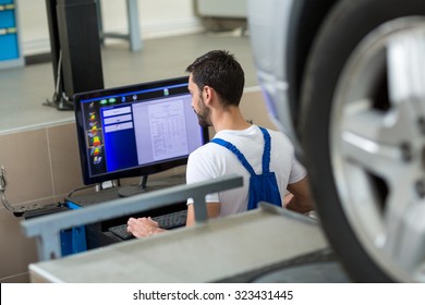 Mechanic Working On Car By Computer In Workshop