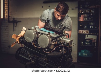 Mechanic Working On Classic Car Engine In Restoration Workshop