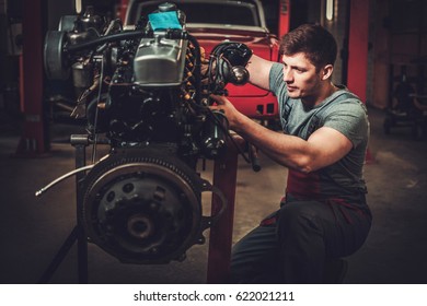 Mechanic Working On Classic Car Engine In Restoration Workshop