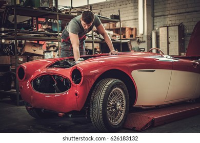 Mechanic Working On Classic Car Electrics In Restoration Workshop