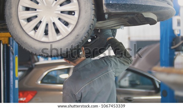 Mechanic working on a tire service on the lift in\
a service station