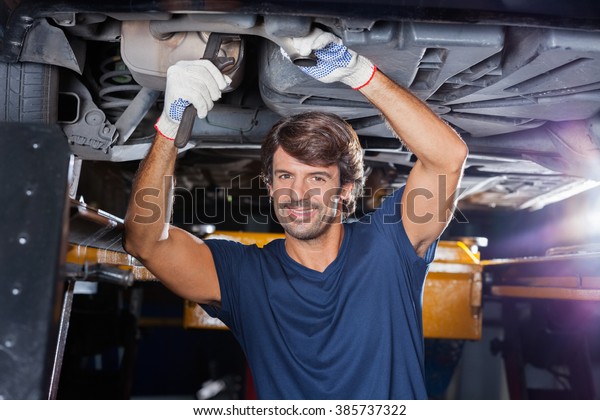 Mechanic Working Under\
Lifted Car At Garage