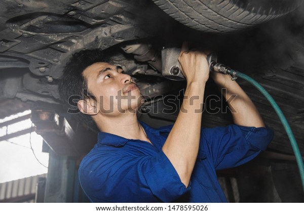 mechanic works below the elevator,\
lifting the car and using the air gun to check the suspension\
system for safety at various points in the service\
center.
