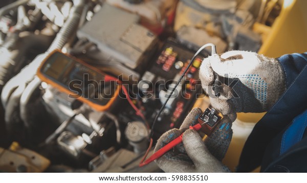 Mechanic works with car electrics - electrical\
wiring, voltmeter
