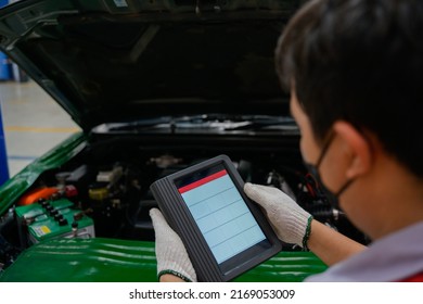 mechanic works at the car service center. Perform a vehicle diagnostic scan using the OBD and OBD2 device on the tablet to fix problems in the garage or repair shop. which is an electronic system