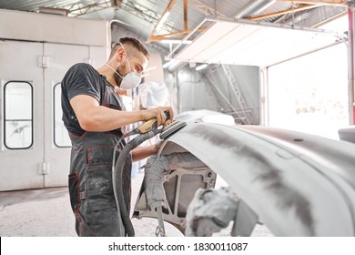 The mechanic works with a grinding tool. Sanding of car elements. Garage painting car service. Repairing car section after the accident.