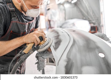 The mechanic works with a grinding tool. Sanding of car elements. Garage painting car service. Repairing car section after the accident. - Shutterstock ID 1830601373