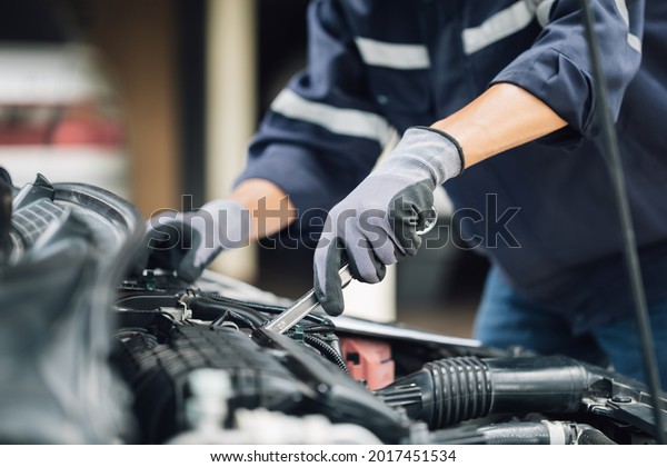 Mechanic works on the engine of the car in the\
garage. Repair service. Concept of car inspection service and car\
repair service.