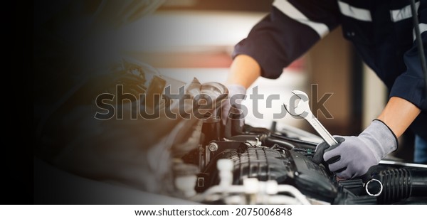 Mechanic works on the engine of the car in the\
garage. Repair service. Concept of car inspection service and car\
repair service.