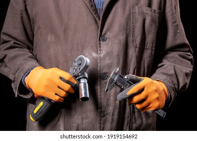 Mechanic With A Wrench And Calipers In Hand. Car Repair Shop Worker With Tools. Dark Background.