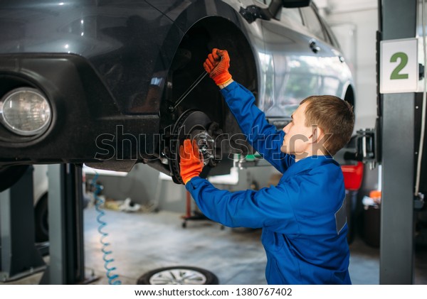 Mechanic with\
wrench repairs the suspension of\
car