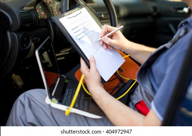 Mechanic writing on clipboard, sitting in the car, close up