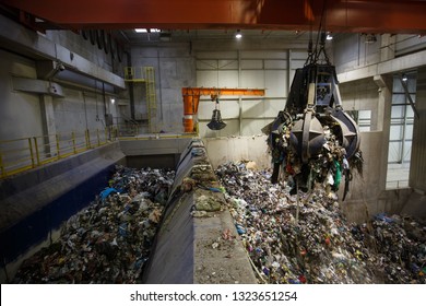 Mechanical claw hand grabbing pile of mixed waste, deposited in the waste treatment plant depot, separation and treatment. Waste disposal, management, reuse, recycle and recovery concept. 
