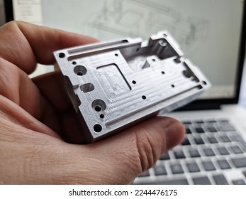 Mechanical engineer hand holding CNC milled custom designed project in front of computer screen and drawings - Shutterstock ID 2244476175