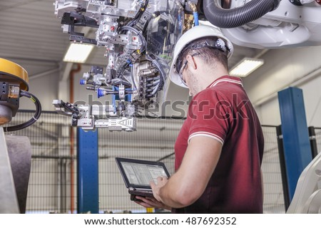 Mechanical Engineer with hard hat and laptap when commissioning a robot