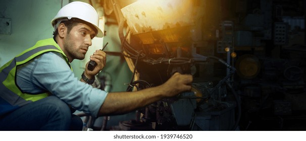 A mechanical engineer or a machine maintenance technician in protective clothing is chatting with a walkie-talkie while preparing to check the machine's readiness within the factory.