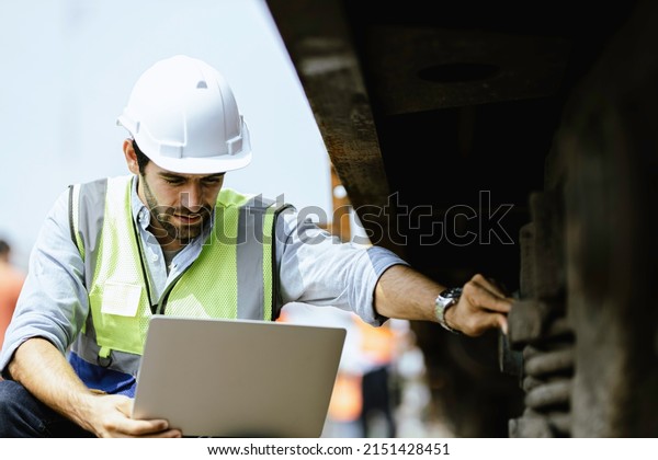 Mechanical engineer or professional maintenance
technician wearing safety clothing is using a wrench to repair and
inspect the undercarriage of the train, have double exposure
images, and bokeh.