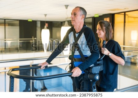 Mechanical exoskeleton. Female physiotherapy doctor helping man with a disability with robotic skeleton to walk. Futuristic rehabilitation, Physiotherapy in a modern hospital