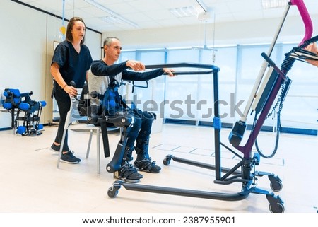 Mechanical exoskeleton. Female physiotherapy doctor assistant lifting man with a disability with robotic skeleton to get up. Futuristic rehabilitation, Physiotherapy in a modern hospital