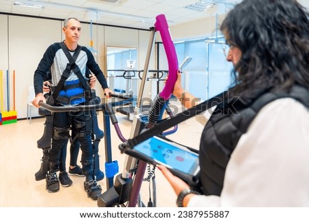 Mechanical exoskeleton. Female physiotherapy medical assistant with man with a disability lifted with robotic skeleton. Futuristic rehabilitation, Physiotherapy in a modern hospital