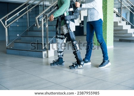 Mechanical exoskeleton, physiotherapist walking with unrecognizable man with a disability with robotic skeleton, physiotherapy in a modern hospital: