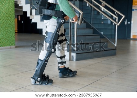 Mechanical exoskeleton, unrecognizable man with a disability walking with the help of robotic skeleton, physiotherapy in a modern hospital, futuristic physiotherapy