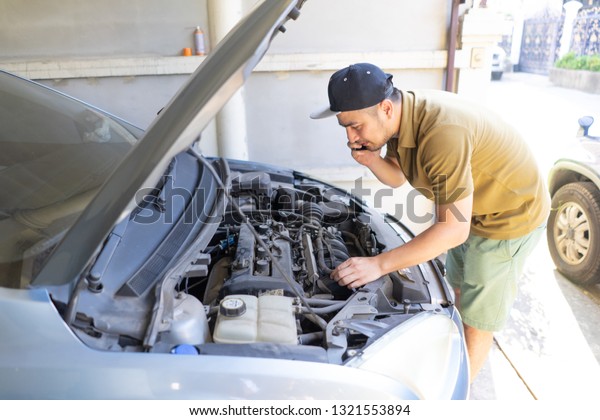 Mechanical fixing car at home. Repairing Service
advice by mobile phone. Mechanic, technician man checking car
engine. Car service, repair, fixing, maintenance working inspection
vehicle concept.