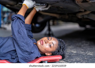 Mechanical girl dirty face wearing overall cover suit lay on garage creeper trolley tighten bolt under car at the car repair shop - Powered by Shutterstock