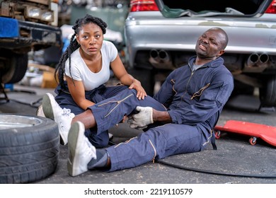 Mechanical Guy At Car Repair Shop Got Accident Sit On The Floor Mechanical Girl First Aid Check His Broken Leg Painful And Emergency Call For Help