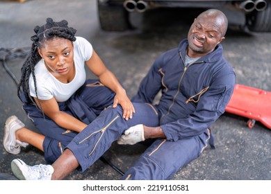 Mechanical Guy At Car Repair Shop Got Accident Sit On The Floor Mechanical Girl First Aid Check His Broken Leg Painful And Emergency Call For Help