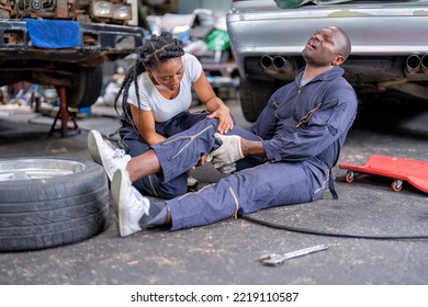 Mechanical Guy At Car Repair Shop Got Accident Sit On The Floor Mechanical Girl First Aid Check His Broken Leg Painful And Emergency Call For Help