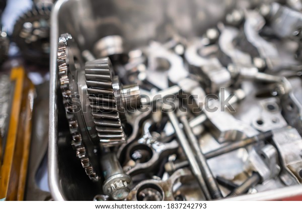 The mechanical guy removes the gear part from the\
diesel engine box and puts on the plate with other nuts and part.\
Diesel engine during service, or maintenance at the garage.\
Service, repair concept