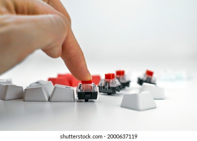 Mechanical keyboard switch on a white background. The person presses the keyboard switch with his finger. Gaming equipment, concept.