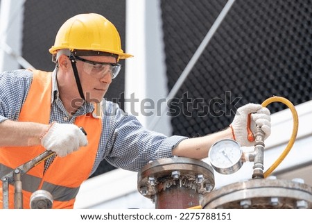 Mechanical maintenance technician inspecting pressure gauge of heating system in heating plant.
