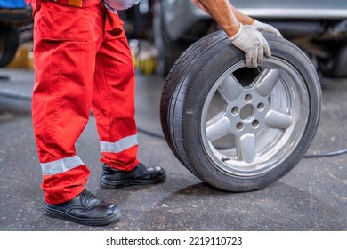 Mechanical Man Standing Roll Alloy Tire To Replace Flat Tire At The Car Repair Shop