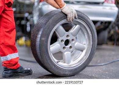 Mechanical Man Standing Roll Alloy Tire To Replace Flat Tire At The Car Repair Shop