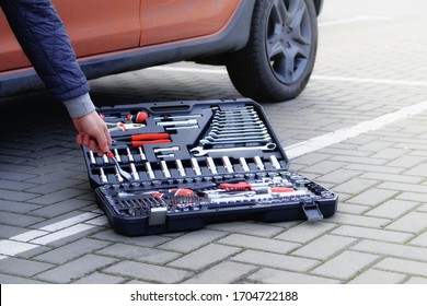 Mechanical Tools Box. Сar Driver Using Different Repair Tools For Repairing And Service An Orange Car. Tool Set Near The Auto. Closeup.