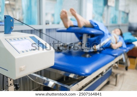 Mechanical traction or decompression tension on the spine, taking pressure off the joints and discs of the spine giving pain relief. Physical therapy technology machine with paint in the background.