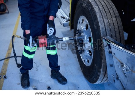 Mechanical workshop operator changing the front wheel of a truck
