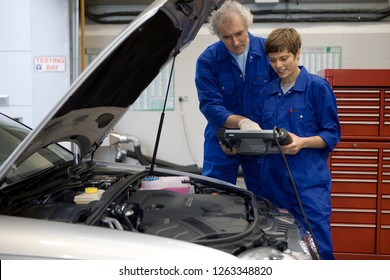 Mechanics with diagnostic computer by car in auto repair garage - Powered by Shutterstock