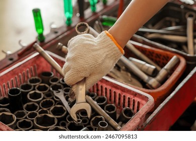 Mechanic's gloved hand picking up wrench from tool tray. Close-up showing tools and organized workspace. Highlights preparation, attention to detail, and readiness in automotive repair tasks. - Powered by Shutterstock