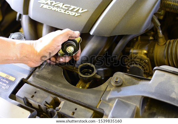 Mechanic\'s hand open Car\
Radiator cap for check water level doing car repair,service or\
maintenance in Lamphun province, North of  Thailand : 23 October\
2019.