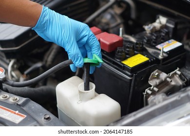 Mechanic's Hand Is Opening Bottle Of Water In Car Engine To Check Auto Car's Coolant Level. Concept : Checking And Maintenance Car Service.      